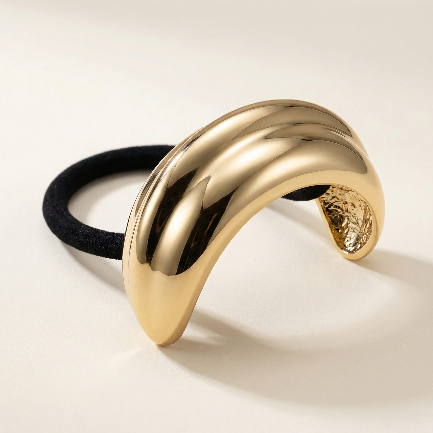 Gold metal pony cuff with black hair tie on a light beige background Snug Strands